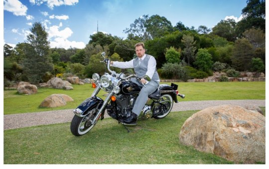 Groom poses on a harley davidson on the rock garden lawn at the National Botanical Gardens